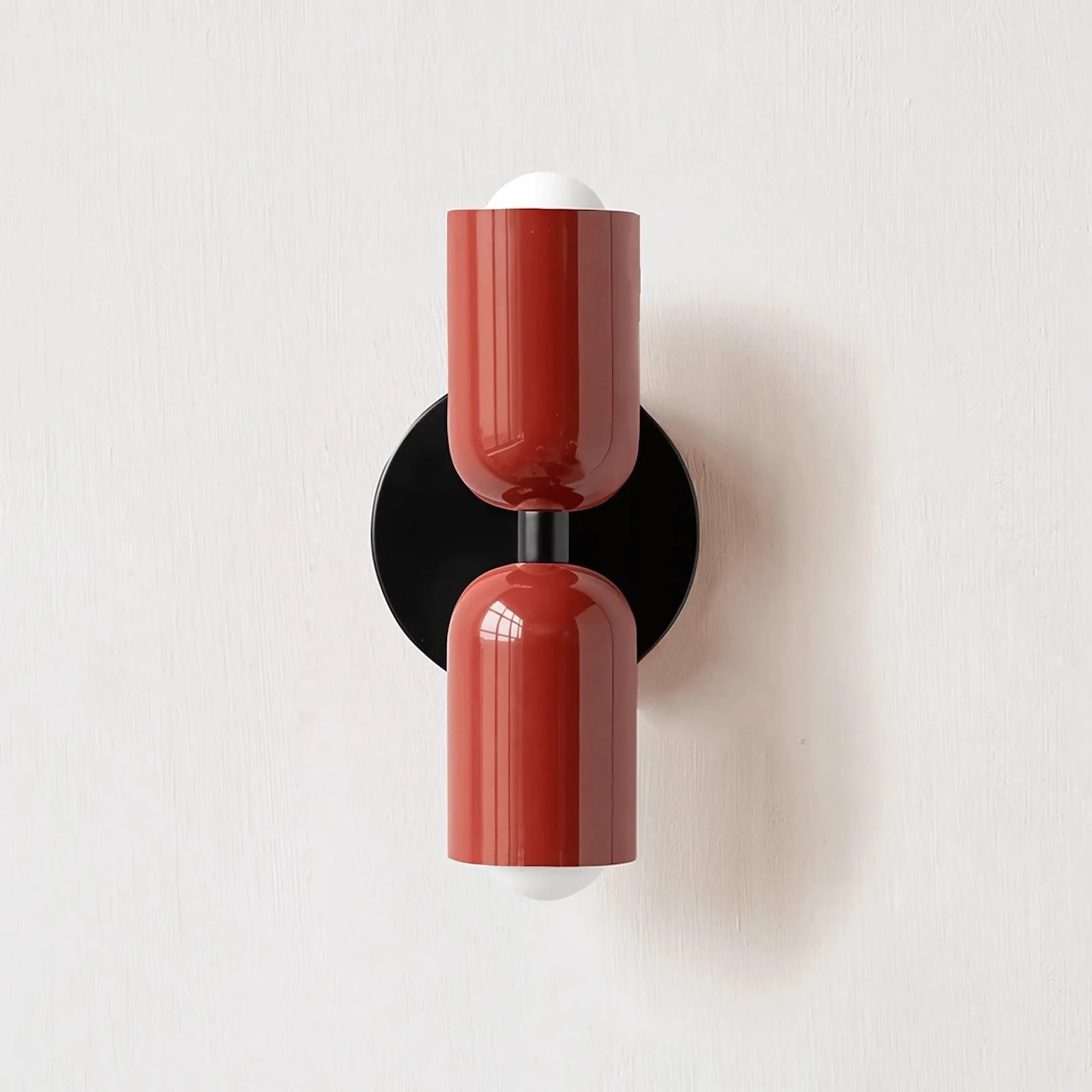 Modern wall sconce with red cylindrical design on a white background